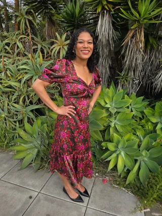 Euri in a floral dress in front of agave and aloe plants