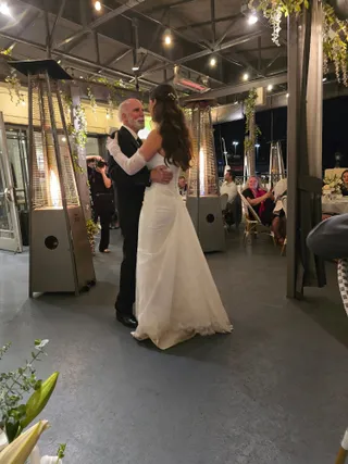 Emma dancing with her father at the reception under the string lights