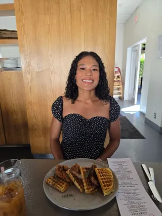 Euri smiling at brunch behind a plate of chicken and waffles
