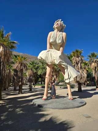Euri standing between the feet of the Forever Marilyn statue