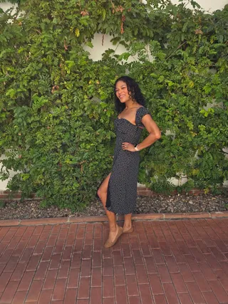 Euri in a polka dot dress in front of a vine-covered wall