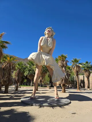 The Forever Marilyn statue against a deep blue sky and palm trees
