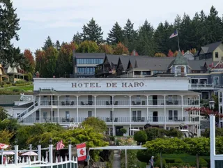 The white Hotel de Haro with its long porches, above the gardens and flags at Roche Harbor