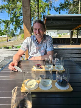 Jereme at a patio table with two wine tasting flights at San Juan Vineyard