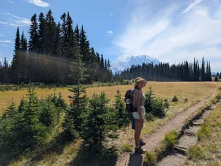 Euri in her straw hat with her hand on her hip, on the trail through Grand Park