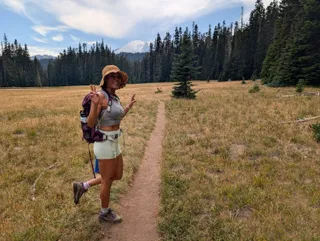 Euri smiling with peace signs on the trail, Mount Rainier in the distance